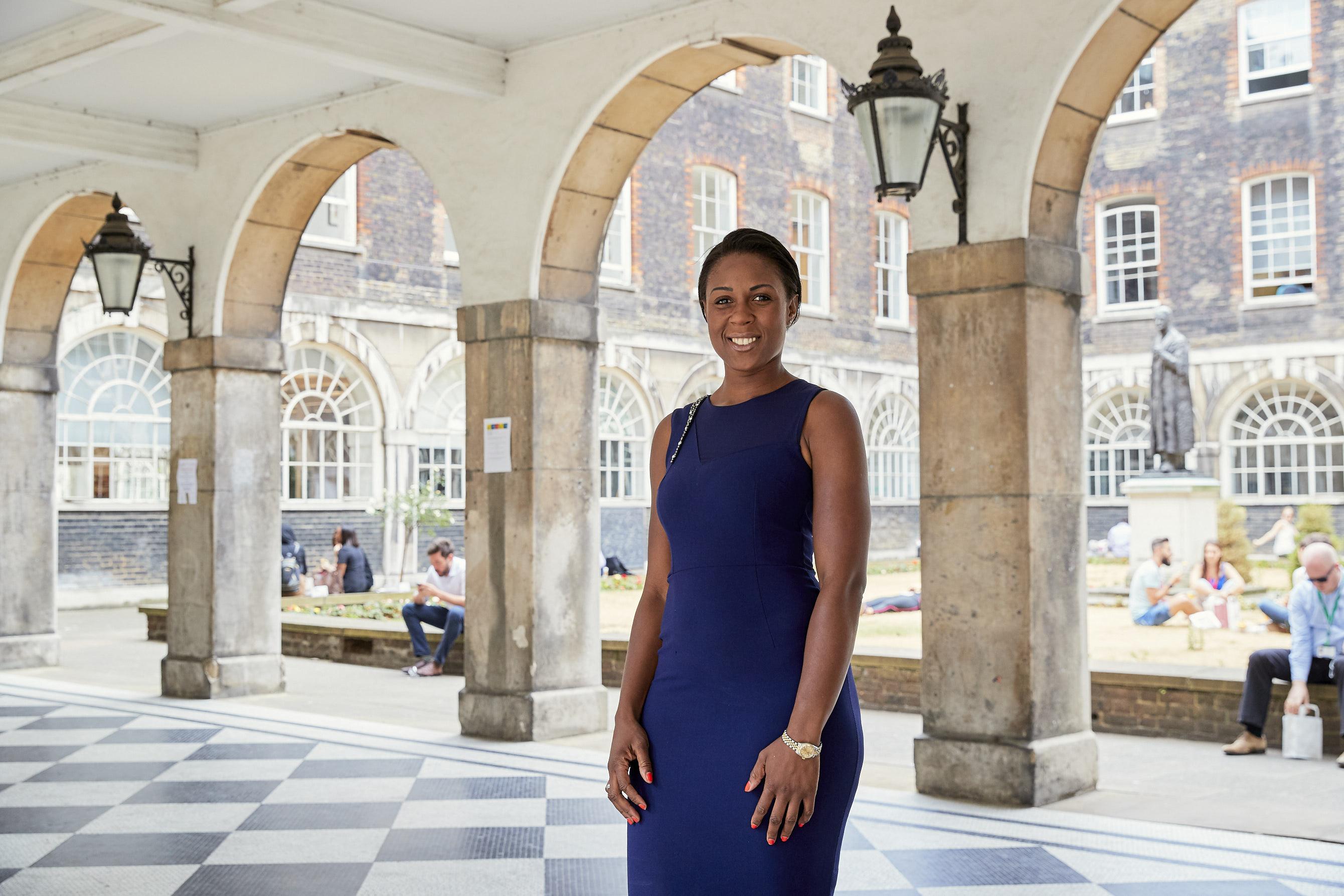 Nadine Antoinette standing in a colonnade courtyard, smiling